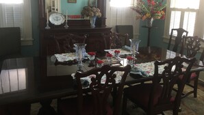Uma sala de jantar com mesa de madeira posta para quatro pessoas, rodeada por cadeiras.