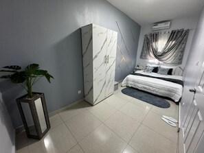 A modern bedroom with a bed, a wardrobe, a potted plant, and a mirror. - Sofana Residence (Dakar)