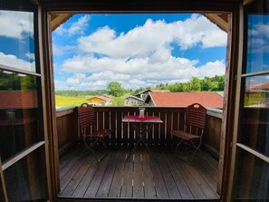 Relax on the deck with a scenic view of the surrounding countryside, featuring a table and chairs.