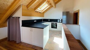 Een moderne keuken met houten balken, een zwart aanrecht en een inbouwoven.