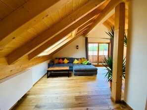 Relax in this inviting attic room with a comfortable sofa, coffee table, and potted plant.
