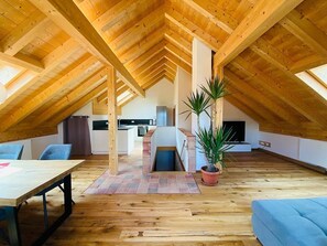 Cozy attic retreat with a high ceiling, wooden table, and comfortable seating area.