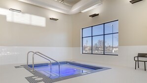 Uma piscina com escada de metal, uma janela com vista e uma cadeira.
