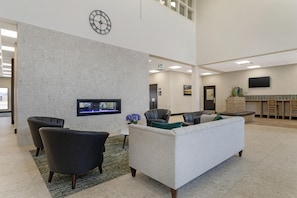 A lobby with a stone wall, a clock, a flat-screen TV, and seating areas.