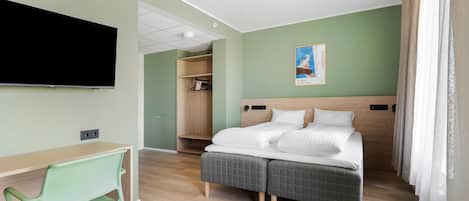 Una habitación de hotel con cama, escritorio, silla, armario y televisor.