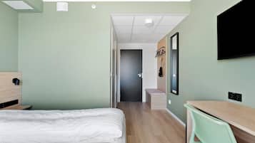 Een hotelkamer met een bed, een bureau, een stoel, een televisie en een deur naar een badkamer.