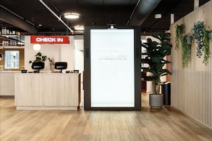 Et receptionsområde med et 'CHECK IN' skilt, en digital skærm og en reception.