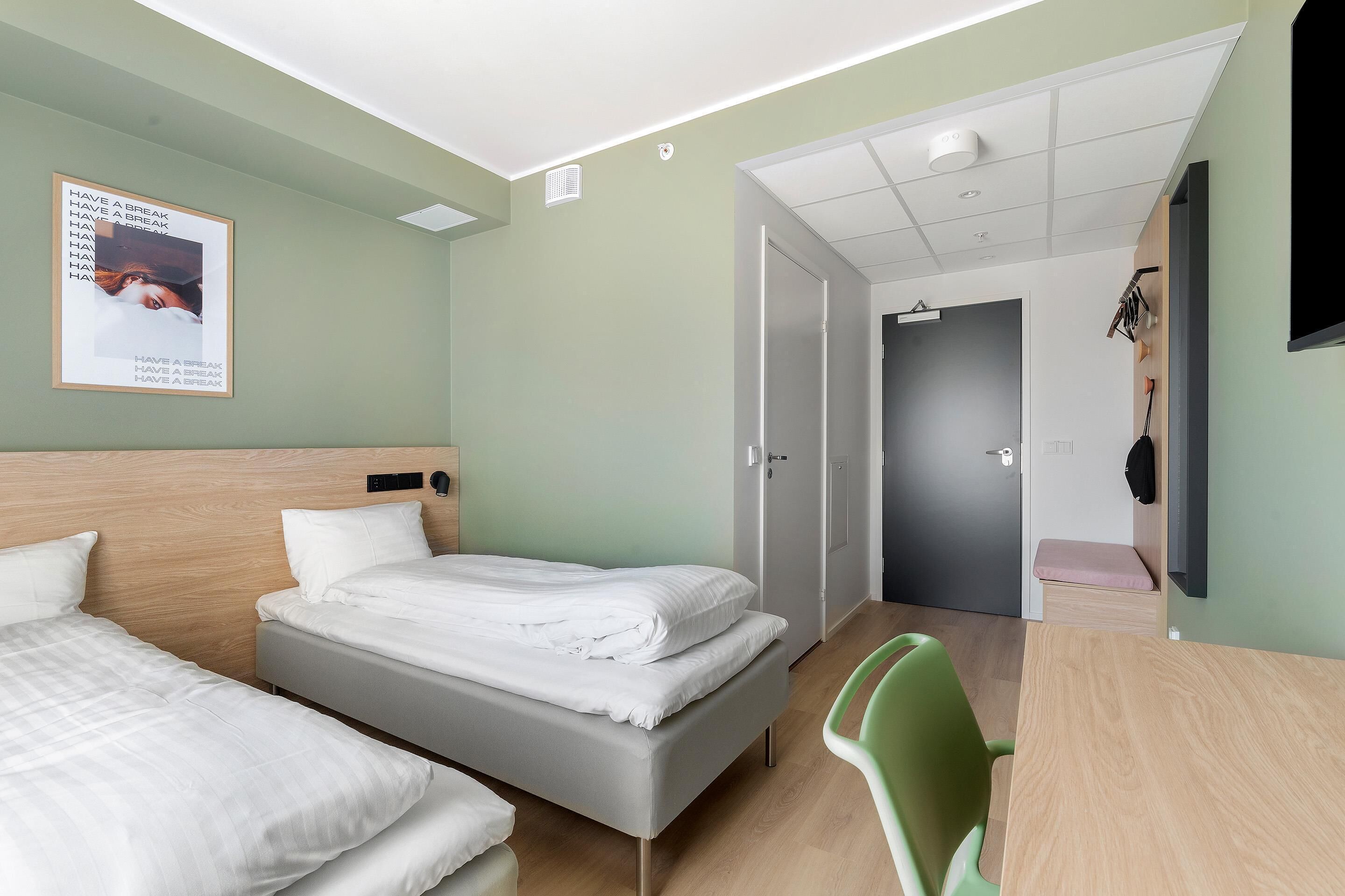 A hotel room with two beds, a desk, and a chair.