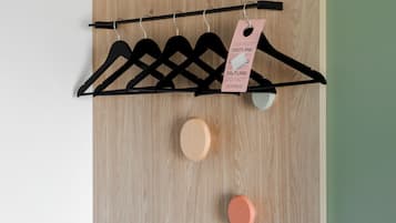 Una pared de madera con un perchero negro que sostiene varios perchas negras y una etiqueta rosa.
