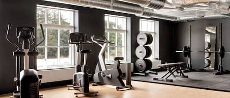 A gym with exercise equipment, large windows, and a mirror.