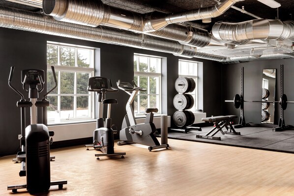 A gym with exercise equipment, large windows, and a mirror. - Aiden By Best Western Odense (Odense)