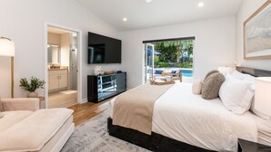 Un dormitorio moderno con una cama grande, un ventilador de techo, un televisor y vistas a una piscina.