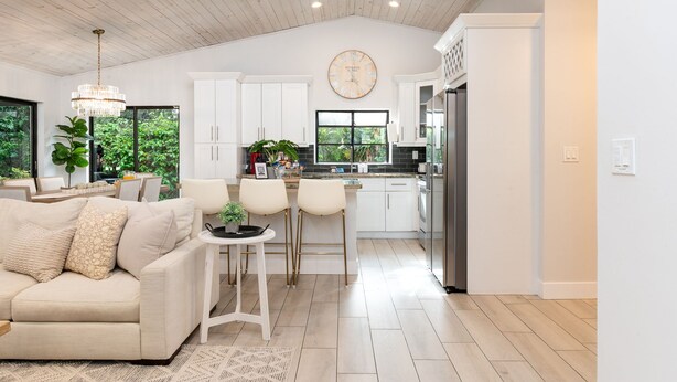 Una cocina moderna con armarios blancos, un reloj grande y vistas a zonas verdes.