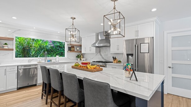 A modern kitchen with white cabinets, a large island with bar stools, stainless steel appliances, and pendant lighting. - Boynton Beach Retreat, Close to Delray, Aug Deal (Boynton Beach)