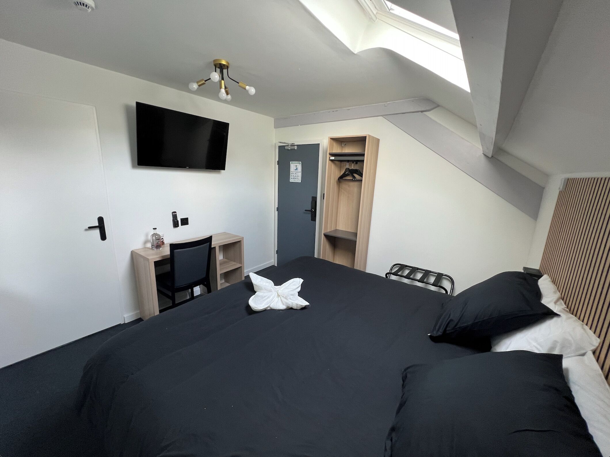 Een slaapkamer met een bed, een televisie, een bureau en een kledingkast.