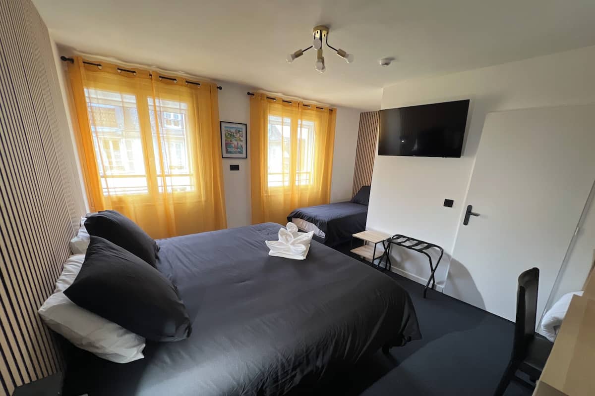 A hotel room with a large bed, a desk, a chair, and a TV mounted on the wall.