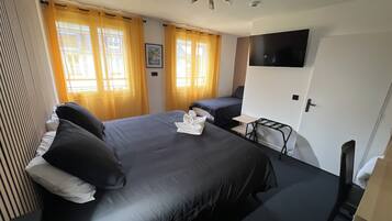 Habitación de hotel con una cama grande, un escritorio, una silla y un televisor montado en la pared.