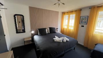 Una habitación de hotel con una cama grande, una mesita de noche, un espejo y un ventilador de techo.
