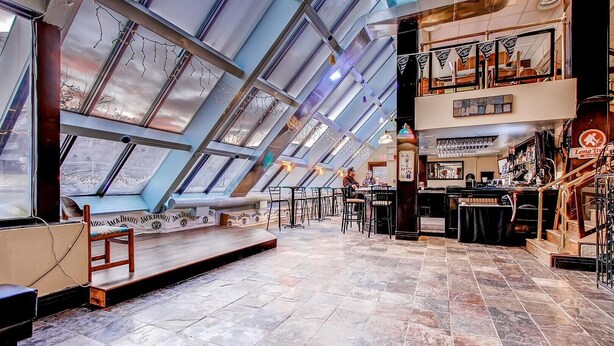 En restaurang med högt i tak och takfönster, med en bardel där ett skylt pryder väggen med texten: ”Länge sen sist”.