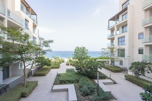 A modern residential building with a central pathway leading to a view of the sea. - Bloomfields 2BR plus Maid Address Residence Fujairah (Al Aqah)