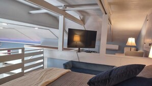 A cozy room with a bed, a TV, and a small seating area.