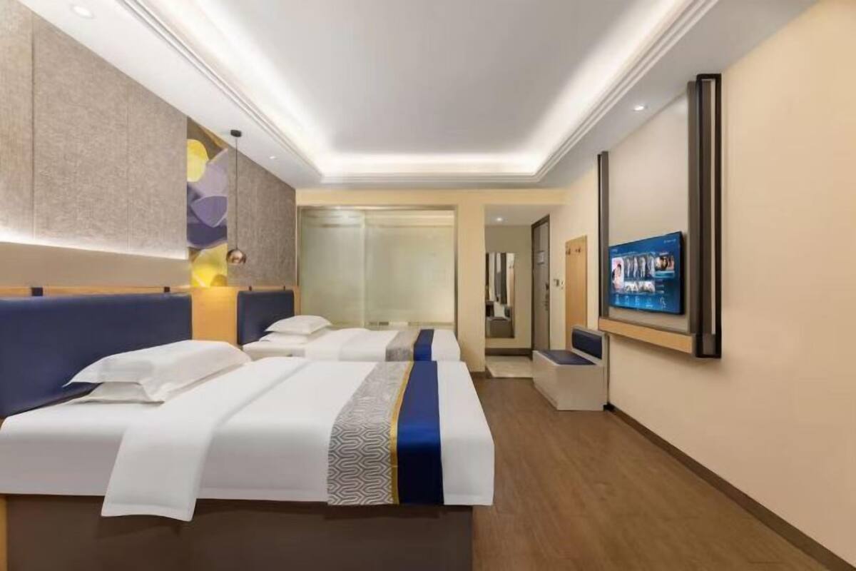 A hotel room with two beds, a TV, and a modern design.