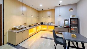 Una cocina moderna con una isla central, iluminación colgante y un comedor con mesa y sillas.