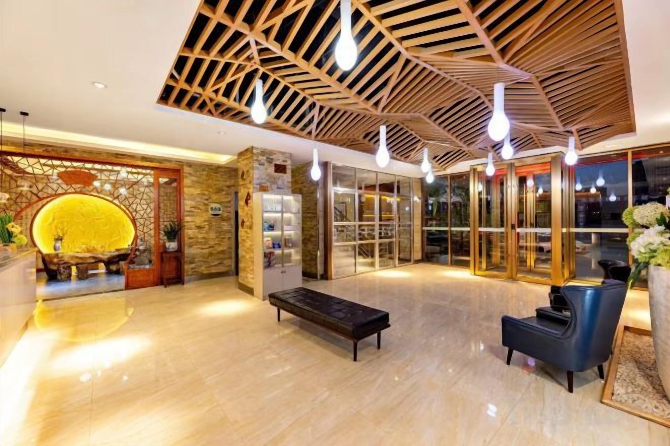 A lobby with a wooden ceiling, a reception desk, a seating area, and a glass door entrance.