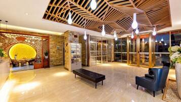 A lobby with a wooden ceiling, a reception desk, a seating area, and a glass door entrance.