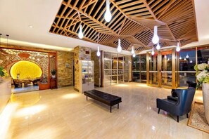 A lobby with a wooden ceiling, a reception desk, a seating area, and a glass door entrance.