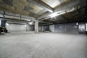 An empty parking garage with concrete floors and walls, multiple parking spaces, and exposed ceiling pipes. - Homeinn Ripple Yun Hotel (Shijiazhuang Xingtang Tangyao Avenue West Bridgehead) (Xingtang)