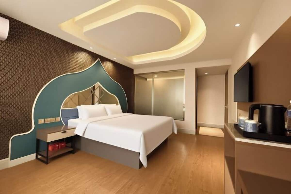 A modern hotel room with a bed, bedside table, and a TV.