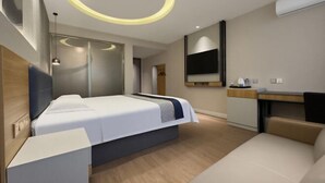 Una habitación de hotel moderna con una cama, un escritorio, una silla, un televisor y una lámpara circular.