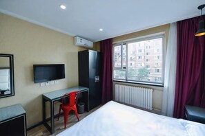 A hotel room with a bed, a desk, a chair, a television, and a window with curtains. - Pebble Hotel (Dalian Xi'an Road Jiaotong University) (Dalian)