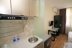 A compact kitchen with a sink, a small table, and a television. - Pebble Hotel (Dalian Xi'an Road Jiaotong University) (Dalian)