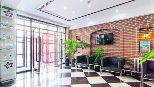 A lobby with a checkered floor, a brick wall, a television, and seating areas. - Pebble Hotel (Dalian Xi'an Road Jiaotong University) (Dalian)