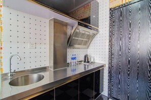 A modern kitchen with a stainless steel sink, a range hood, and a patterned backsplash. - Pebble Hotel (Dalian Xi'an Road Jiaotong University) (Dalian)