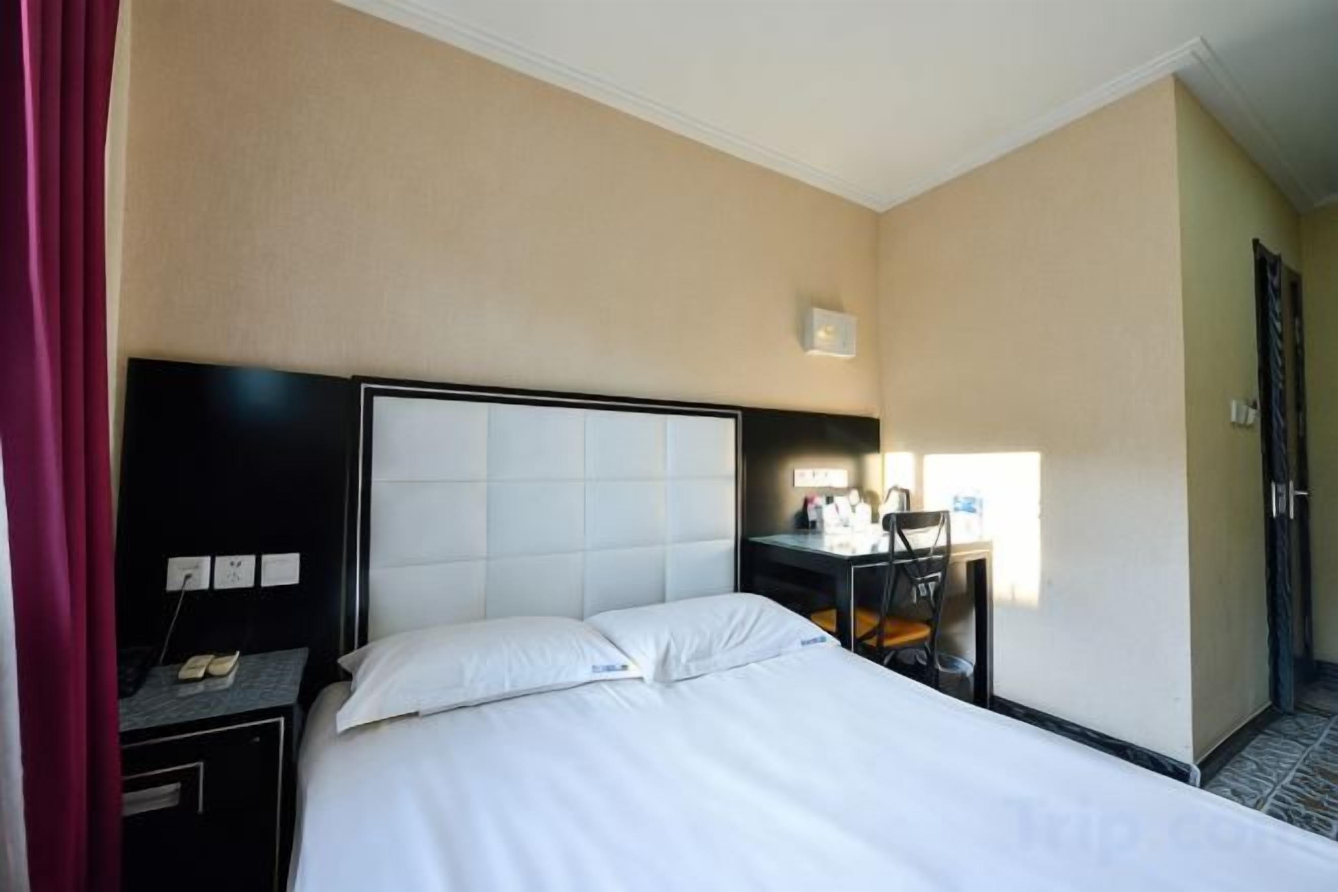 A hotel room with a bed, a desk, and a chair.