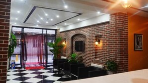 A lobby with a checkered floor, brick walls, and a red carpet leading to the entrance. - Pebble Hotel (Dalian Xi'an Road Jiaotong University) (Dalian)