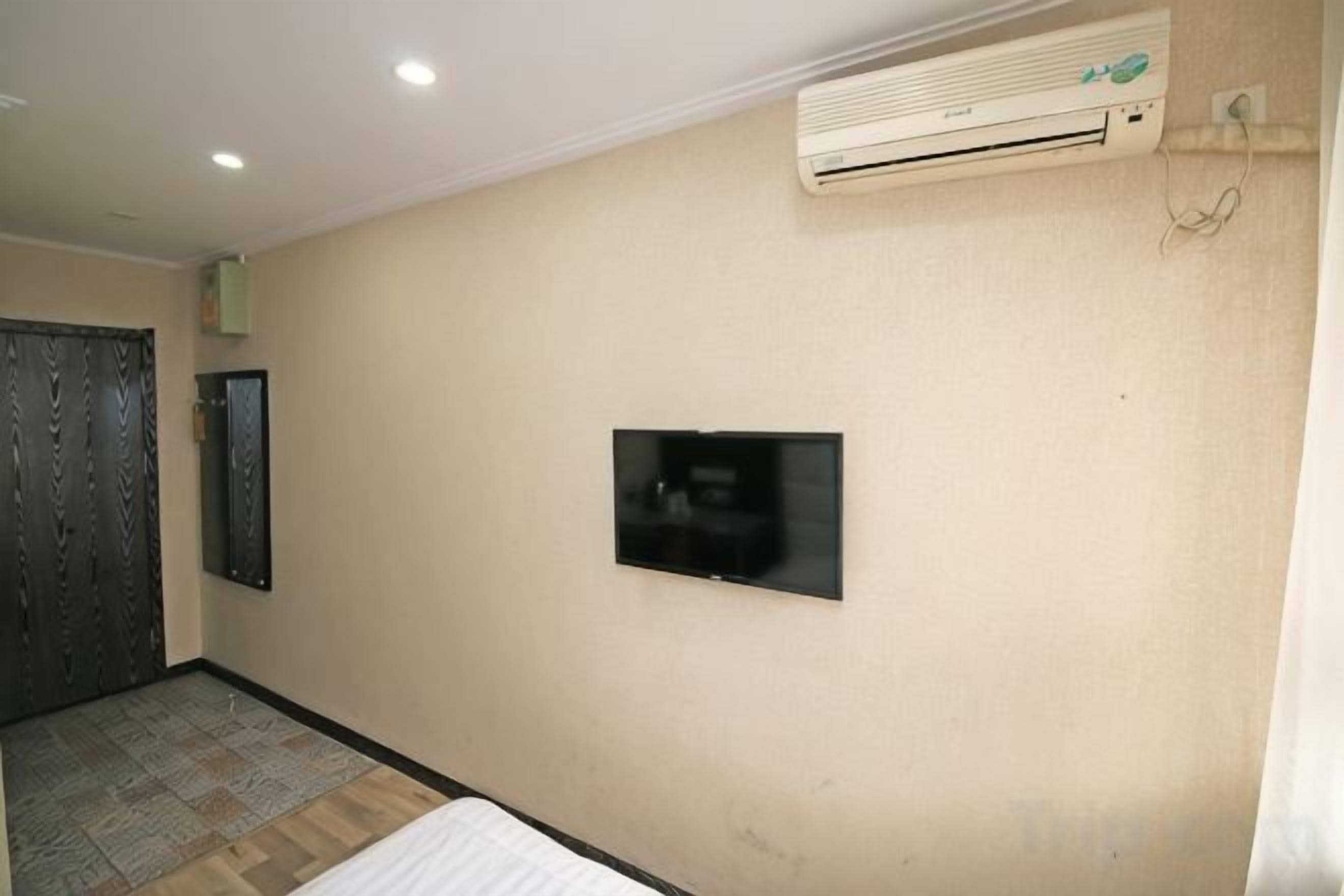 Ein Zimmer mit einem wandmontierten Flachbildfernseher, einer Klimaanlage und einem gemusterten Boden.