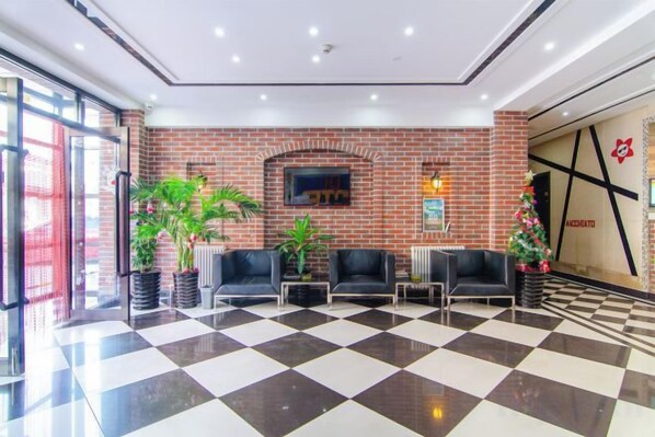 A lobby with a checkered floor, brick wall, seating area, and a Christmas tree.