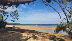 Ein Strand mit blauem Himmel, ruhigem Wasser und Booten.
