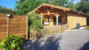 Eine Holzhütte mit Veranda, einem eingezäunten Bereich und einem Schotterweg.
