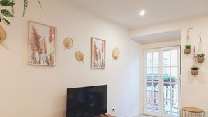 A living room with a flat-screen TV, decorative wall art, and a checkered rug.