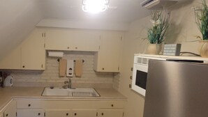 A kitchen with white cabinets, a stainless steel refrigerator, and a brick accent wall. - Enjoyable Sunny 2-bedroom apartment with WiFi in Fall River Historical District (Fall River)