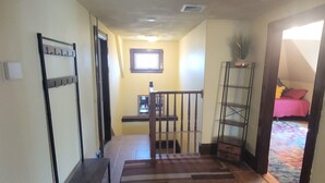 A hallway with a staircase leading to a bedroom. There is a coat rack, a small table, and a plant on the wall. - Enjoyable Sunny 2-bedroom apartment with WiFi in Fall River Historical District (Fall River)