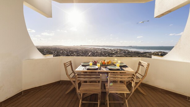 A dining area with a table set for two, overlooking a coastal landscape. - Baleal Blue Sky - Ocean View (Peniche)