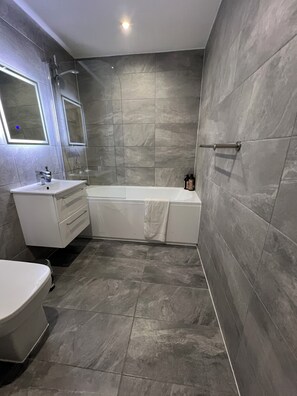 A modern bathroom with a bathtub, a sink, and a toilet.
