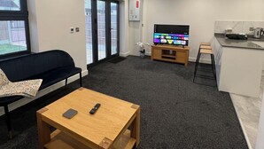 Una sala de estar moderna con sofá, mesa de centro, televisor y zona de cocina.