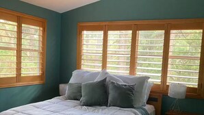 A bedroom with a bed, a ceiling fan, and windows with blinds.